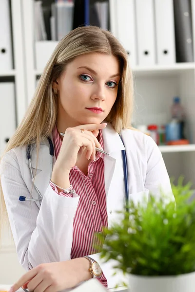 Schön lächelnde Ärztin sitzt am Arbeitsplatz — Stockfoto