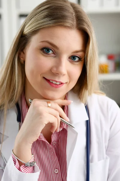 Szép női orvos sit munkahelyen mosolyogva — Stock Fotó