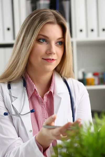 Mooie glimlachend vrouwelijke arts sit op werkplek — Stockfoto