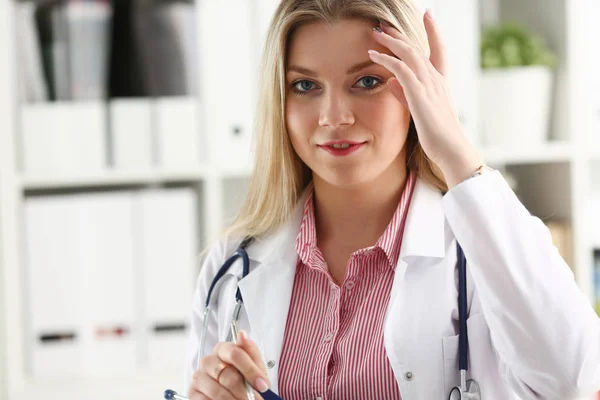 Belle femme souriante médecin assis au travail — Photo