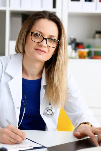 Schön lächelnde Ärztin sitzt am Arbeitsplatz — Stockfoto