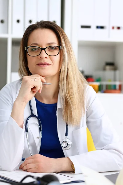 Schön lächelnde Ärztin sitzt am Arbeitsplatz — Stockfoto