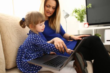 Sevimli küçük kız anne kullanım dizüstü bilgisayar ile kanepede