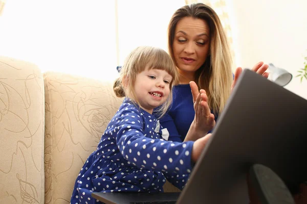 Linda niña en el sofá con el ordenador portátil de uso mamá —  Fotos de Stock