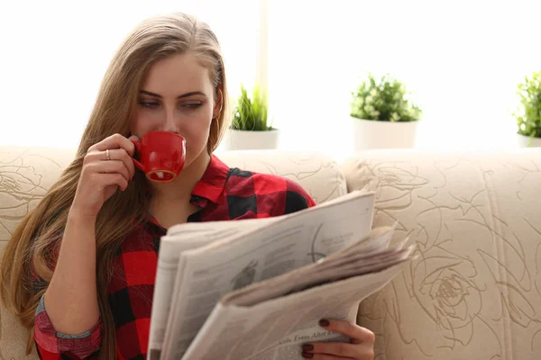 Женщина пьет кофе и читает сидеть на диване — стоковое фото