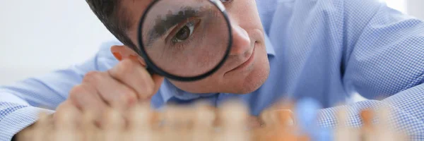 A businessman in blue shirt is holding a magnifying glass — Stock Photo, Image