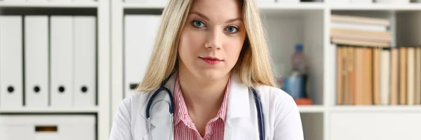 Bella sorridente medico femminile sedersi sul posto di lavoro — Foto Stock
