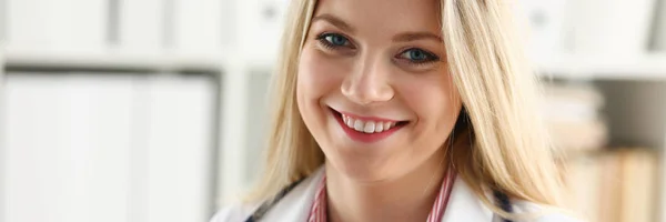 Красивая улыбающаяся женщина врач сидит на рабочем месте — стоковое фото