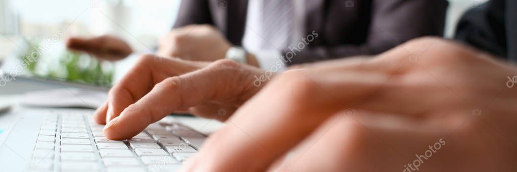 Male arms in suit typing on white