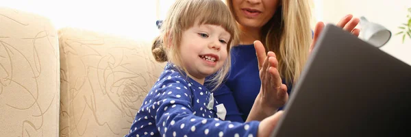 Linda niña en el sofá con el ordenador portátil de uso mamá — Foto de Stock