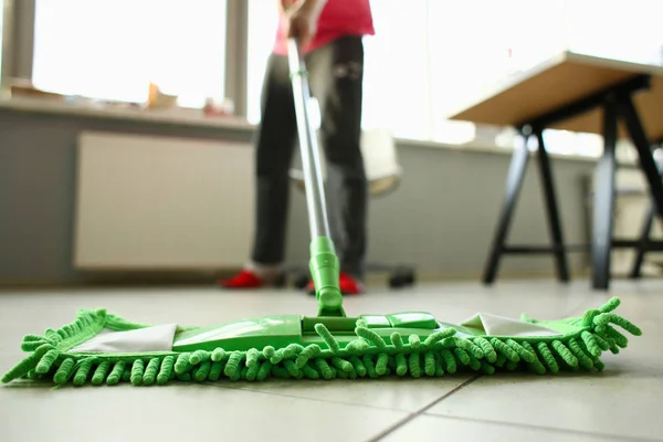 Green plastic mop cleaning laminated light dirty floor