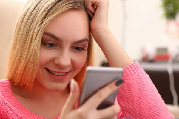 Jovem bonita loira womansit no sofá segurar smartphone em mãos — Fotografia de Stock