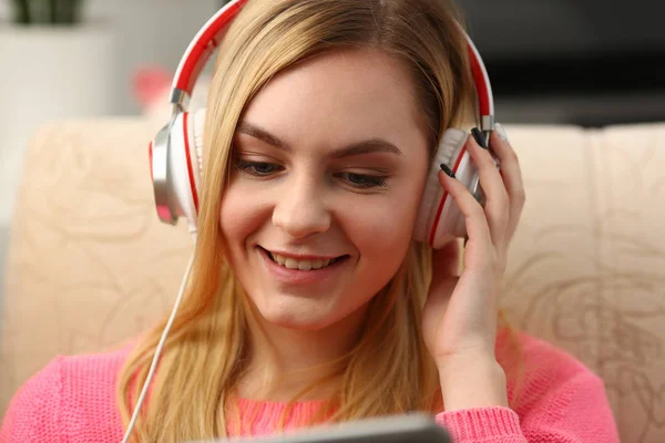 Młody piękny blond kobieta siedzieć na kanapie w salon tabletki trzymać w ramionach słuchać muzyki — Zdjęcie stockowe