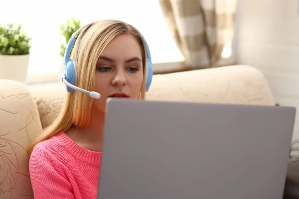 Jovem bela mulher loira sentar-se no sofá na sala de estar segurar laptop nos braços ouvir música — Fotografia de Stock