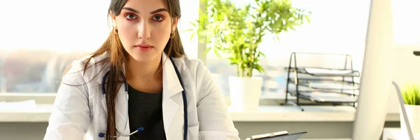 Bella sorridente medico femminile sedersi sul posto di lavoro — Foto Stock