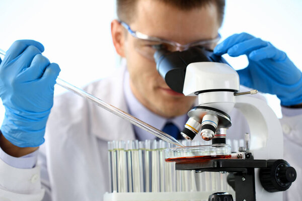 Portrait of a young chemist looking in binocular