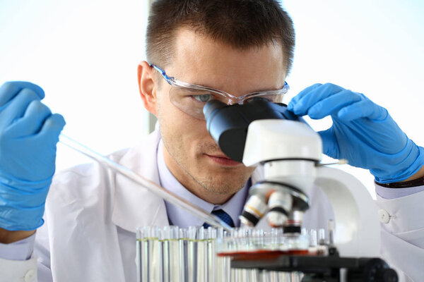 Portrait of a young chemist looking in binocular