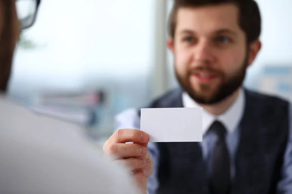 Male arm in suit give blank calling card to visitor