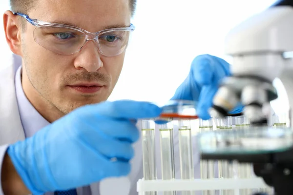 Un químico masculino sostiene un tubo de ensayo de vidrio en su mano —  Fotos de Stock