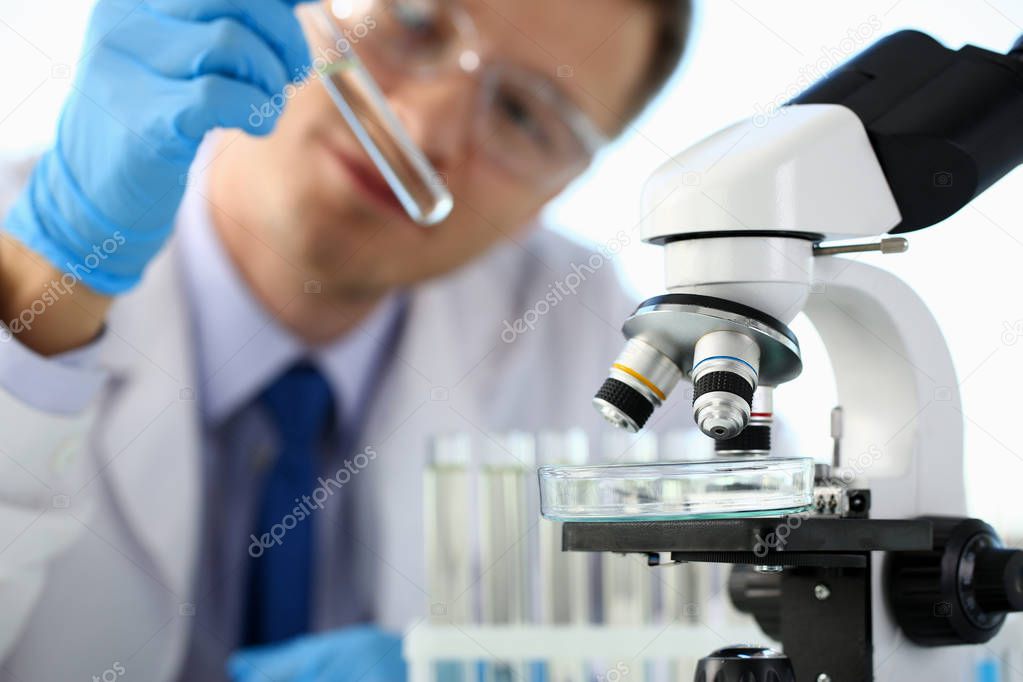 A male chemist holds test tube of glass in his hand