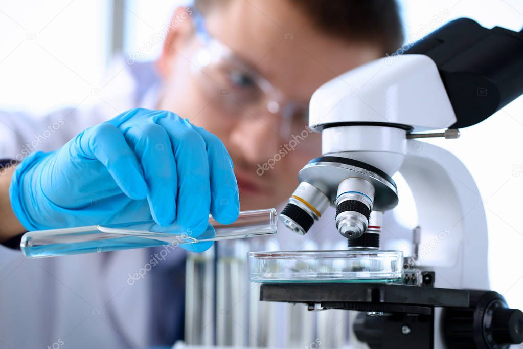 A male chemist holds test tube of glass in his hand