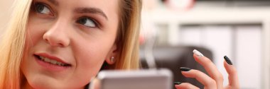 Genç sarışın womansit kanepe tutun Smartphone elinde güzel