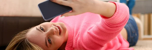 Jonge mooie vrouw hebben een rust liggen op de vloer houden smartphone in armen — Stockfoto