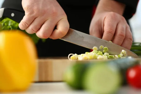 Cook holds knife in hand and cuts on