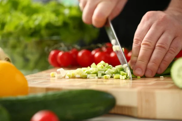 Cook holds knife in hand and cuts on