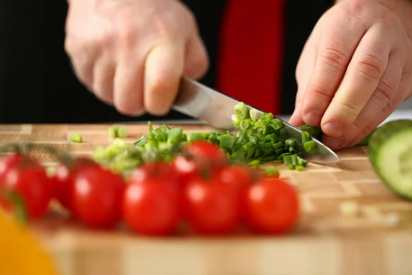 Cook holds knife in hand and cuts on