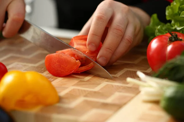 Cook holds knife in hand and cuts on