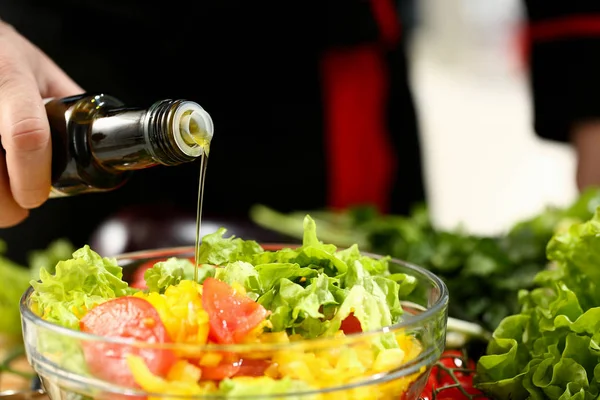 Koch hält Flasche in der Hand und tröpfelt Olivenöl — Stockfoto