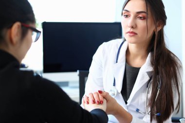 Genç kadın doktor hasta el ile tutar