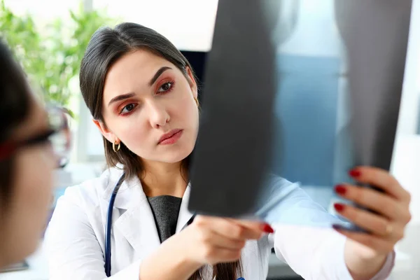 Schöne Ärztin im Arm halten und Röntgen anschauen — Stockfoto