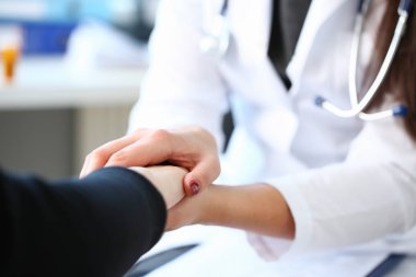 Genç kadın doktor hasta el ile tutar