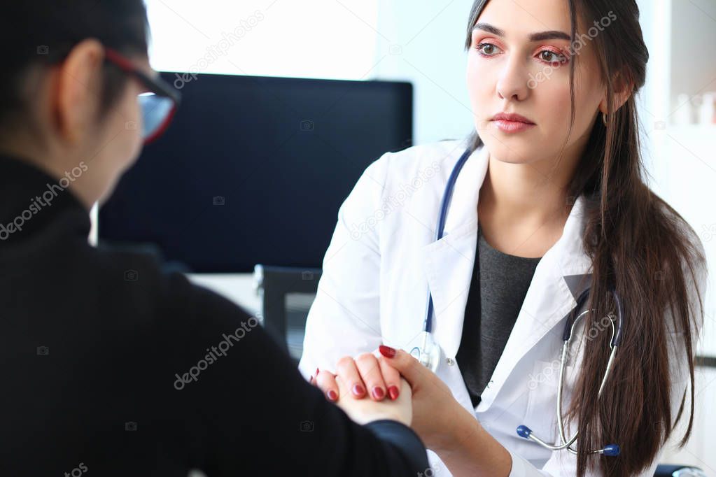 Young female doctor holds sick patient by hand