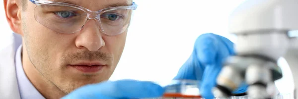 Un chimiste masculin tient dans sa main un éprouvette de verre — Photo