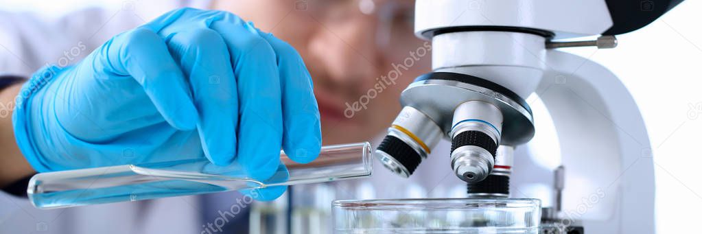 A male chemist holds test tube of glass in his hand