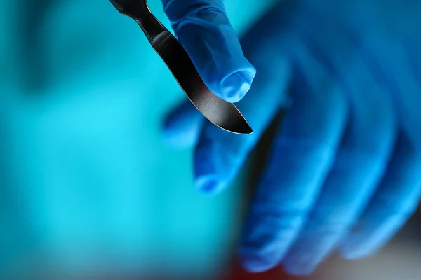 Braços de cirurgião em uniforme estéril segurando faca afiada — Fotografia de Stock