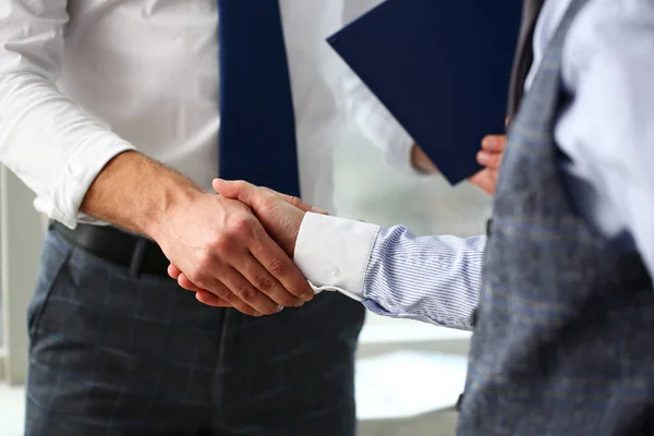 Man in suit and tie give hand as hello in office closeup