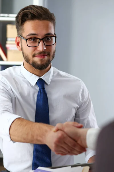 Man in suit and tie give hand as hello in office