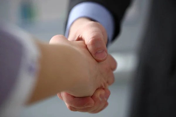 Man in suit and tie give hand as hello in office