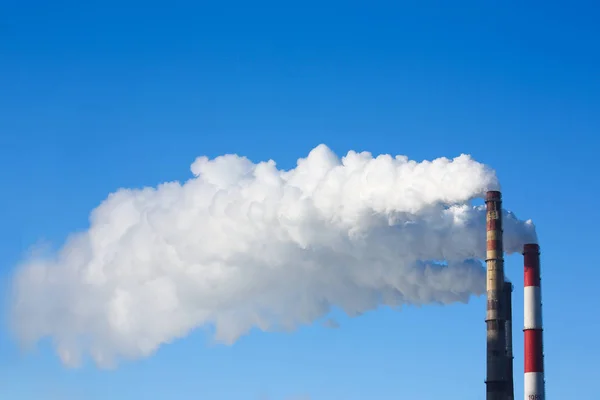 La fumée blanche provient des tuyaux contre le ciel bleu — Photo