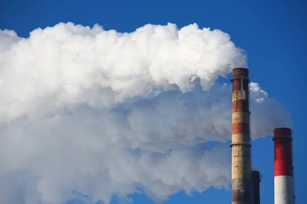 La fumée blanche provient des tuyaux contre le ciel bleu — Photo