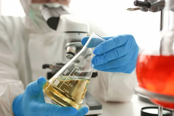 Químico masculino olhar para microscópio segurar tubo de ensaio — Fotografia de Stock