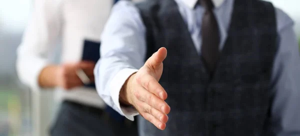 Man in suit and tie give hand as hello in office