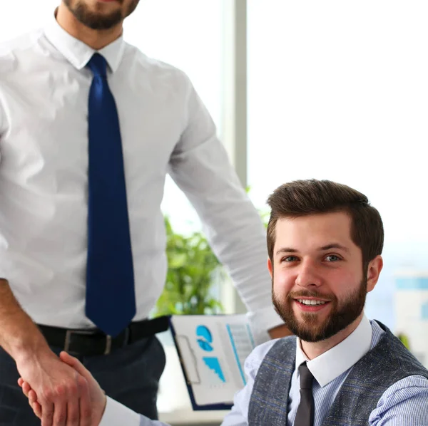 Man in suit and tie give hand as hello in office