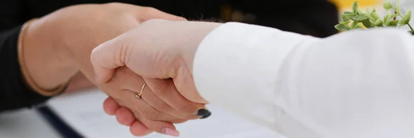 Man and woman shake hands as hello in office