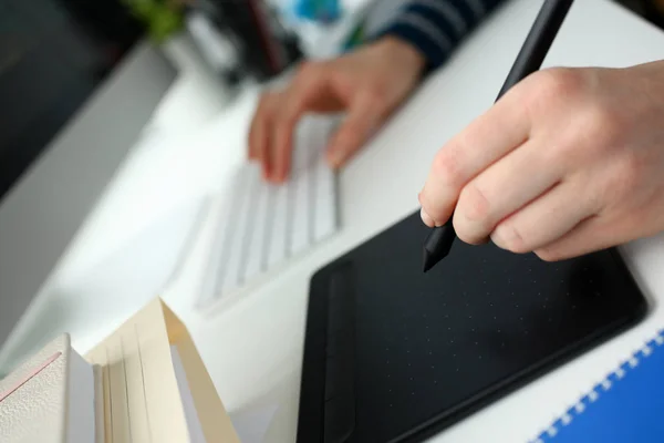 Ein junger Designer hält einen Stift von einem Tablet in der Hand — Stockfoto