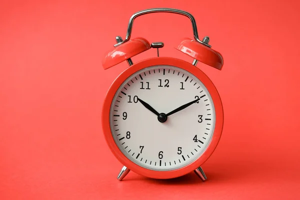 Reloj despertador viejo de coral sobre fondo rojo — Foto de Stock